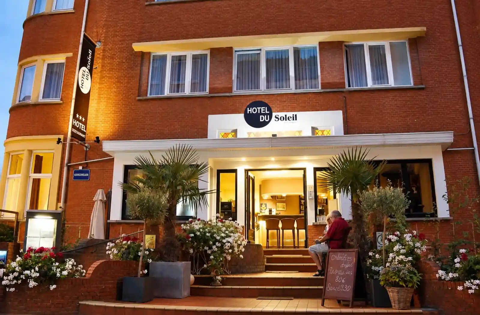 Bakstenen gevel en verlichte ingang van Hotel du Soleil